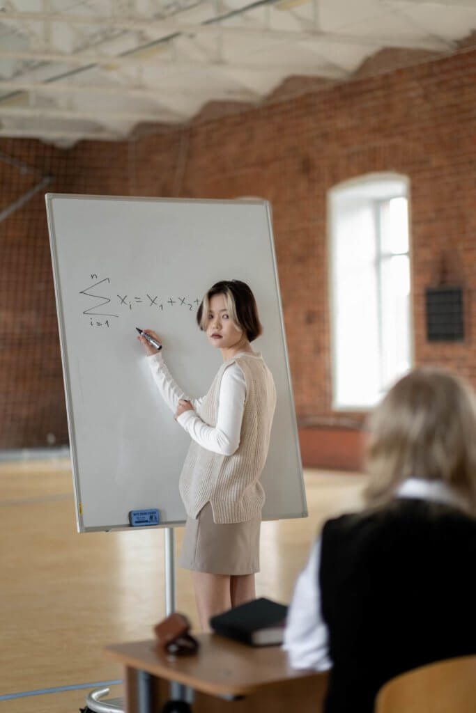 a student solving an algebra problem on a white board